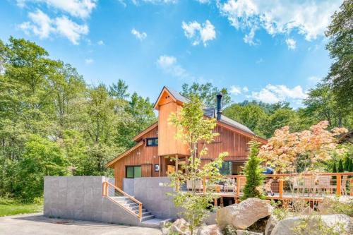 a wooden house in the woods with a patio at Sakura 88 - Luxury Villa - 280sqm 4 bedrooms in Hakuba