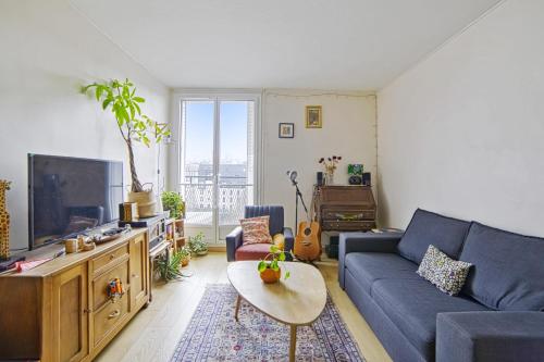 un salon avec un canapé bleu et une télévision dans l'établissement Appartement Tandou - Welkeys, à Paris