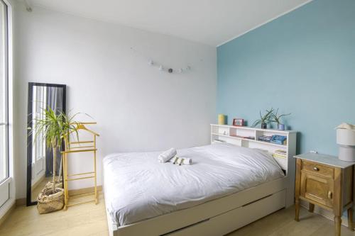 une chambre avec un lit avec un mur bleu dans l'établissement Appartement Tandou - Welkeys, à Paris