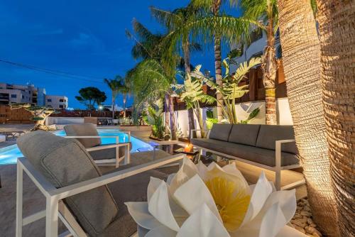 a resort patio with chairs and a pool with palm trees at [2 min from the sea] pool, comfort and free WiFi in Miami Platja