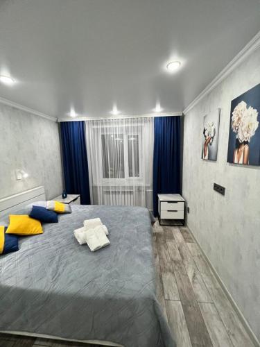 1 dormitorio con 1 cama grande con almohadas azules y amarillas en Квартира премиум класса, en Semey