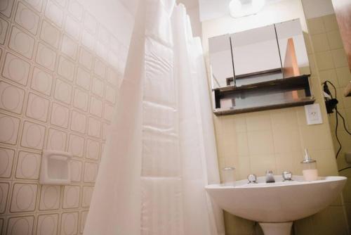 a bathroom with a sink and a white shower curtain at Avenida España Apartments. Pleno centro de Mendoza in Mendoza