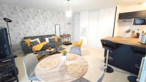 sala de estar con mesa y sofá en Appart Poissy Relax Wi-Fi Pool by Servallgroup, en Carrières-sous-Poissy