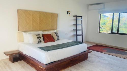 um quarto com uma cama com almofadas e uma janela em Luana suites- Suite Koya em Zihuatanejo