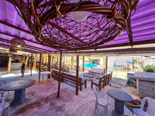 a restaurant with tables and chairs and a purple ceiling at Hotel Pousada Mahon Mar in Praia do Frances