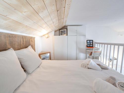 - une chambre avec un lit blanc et un plafond en bois dans l'établissement Studio avec mezzanine, retour skis aux pieds, proche remontée mécanique - FR-1-645-28, à Huez