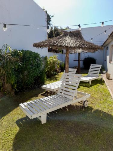 two white lounge chairs and a straw umbrella at Sur Hotel in Necochea