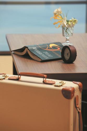 a book on a table with a vase of flowers at Bayside Square Kaike Hotel in Yonago