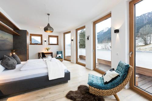 a bedroom with a bed and a chair and windows at Chalet am Breitenberg Appartement CB 12 in Pfronten