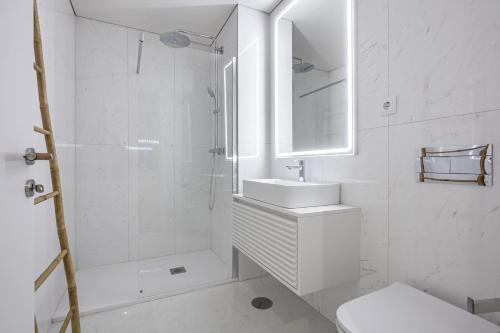 a white bathroom with a sink and a shower at Apartamento Vista Mar in Canidelo