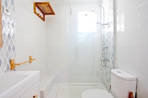 a white bathroom with a shower and a toilet at Apartamento SofiSara in Tavira