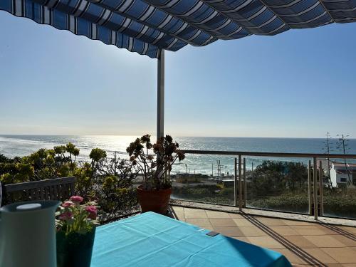 a view of the ocean from a patio with a table at Mega Ocean Magoito - Sintra in Sintra