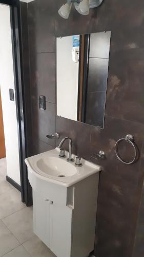 La salle de bains est pourvue d'un lavabo blanc et d'un miroir. dans l'établissement Departamento Santa Teresita, à Santa Teresita