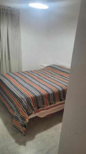 una cama con una manta colorida sentada en el suelo en Departamento Santa Teresita en Santa Teresita