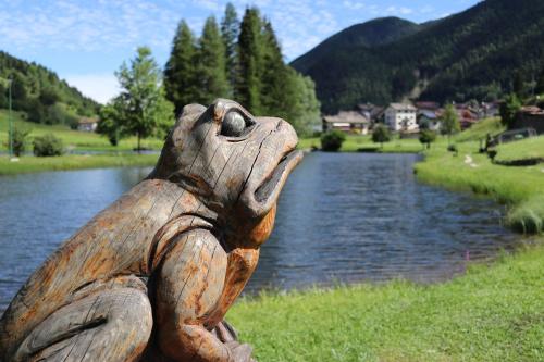 a statue of a frog standing next to a river at B&B Relais Dolomiti in Bedollo