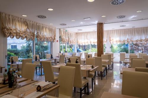 una sala da pranzo con tavoli, sedie e finestre di Hotel Palma de Majorca a Bibione