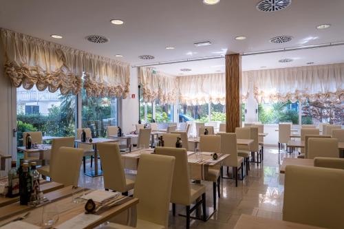 a dining room with tables and chairs and windows at Hotel Palma de Majorca in Bibione