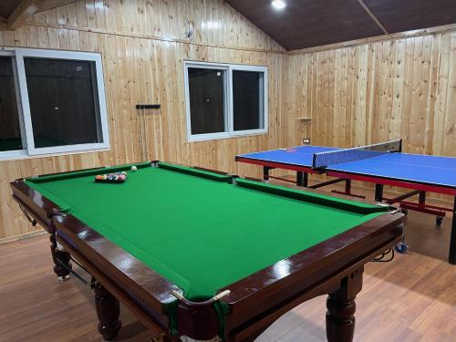 two pool tables in a room with wooden walls at Atulyam, Pangot in Nainital