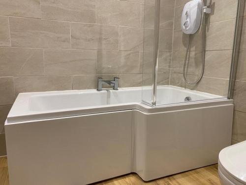 a white bath tub in a bathroom with a phone on the wall at The Ancient Briton in Pen-y-cae