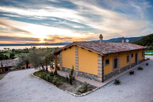 a small yellow house with a sunset in the background at Agriturismo Parco di Canuleio - con vista sul Lago in Bolsena