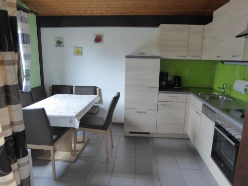 eine Küche mit einem Tisch, Stühlen und einem Waschbecken in der Unterkunft Behringer in Immenstaad am Bodensee