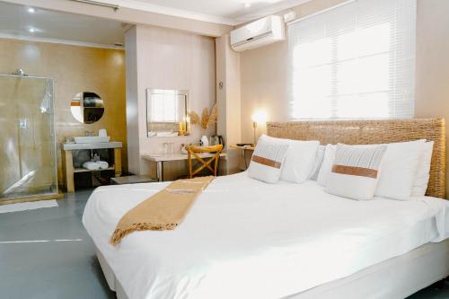 1 dormitorio con 1 cama blanca grande con almohadas blancas en Lighthouse Guesthouse & Cafe, en Groblersdal