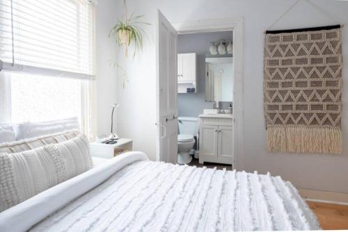 a white bedroom with a bed and a bathroom at Deluxe Cute Apt Walk to Restaurants in Winooski
