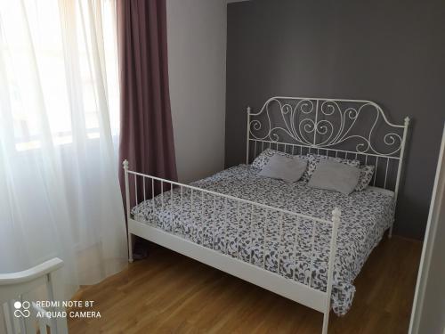 1 dormitorio con cama blanca y cabecero de metal en Apartman 9, en Voždivac