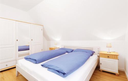 a white bedroom with a large bed with blue pillows at Reetdachhaus Moin-moin in Kutzow