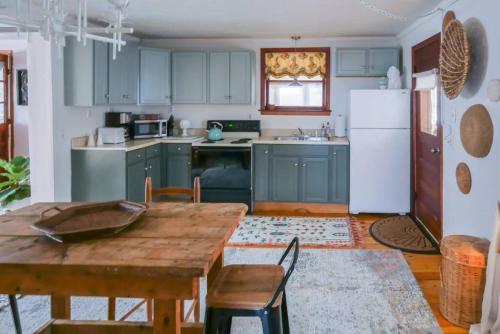 a kitchen with green cabinets and a wooden table at Bohemian Bungalow with Hot Tub in Winooski