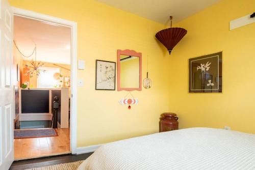 a bedroom with a white bed and a yellow wall at Postmodern Penthouse 1 Min Walk Dining and Shops in Winooski