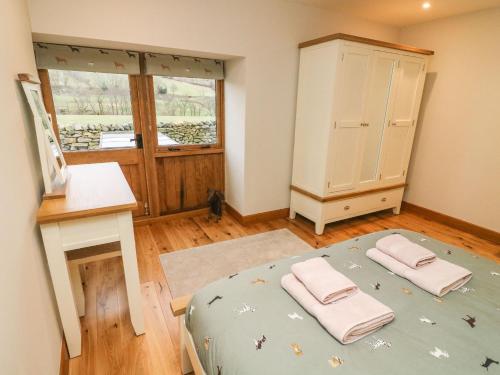 a bedroom with a bed and a dresser and a window at Hollowgill Barn in Sedbergh