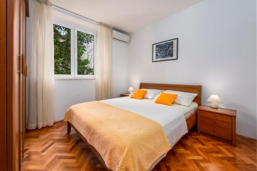 sypialnia z łóżkiem z 2 pomarańczowymi poduszkami w obiekcie Bulevar Apartments w Dubrowniku