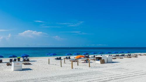 a beach with umbrellas and chairs and the ocean at Two-Bedroom Apartment in Orange Beach