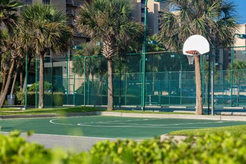 a tennis court with palm trees and a basketball hoop at Two-Bedroom Apartment in Orange Beach