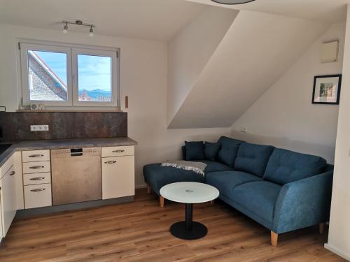 - un salon avec un canapé bleu et une table dans l'établissement Ferienwohnung im Obstgarten, à Achberg