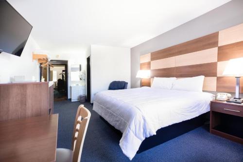 ミノクアにあるNorthwoods Inn & Suites Minocquaのベッド、デスク、テレビが備わるホテルルームです。