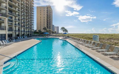 a swimming pool with chairs and a building at One-Bedroom Apartment in Orange Beach