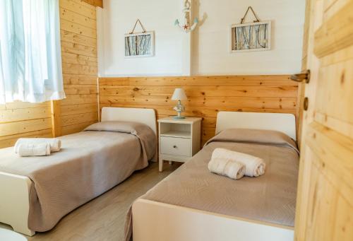 two beds in a room with wooden walls at Casa Vacanze La Fenice - Casa Atlantica in Cava dʼAliga