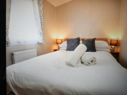 a bedroom with a white bed with towels on it at 32 Bayview Oceans Edge in Morecambe