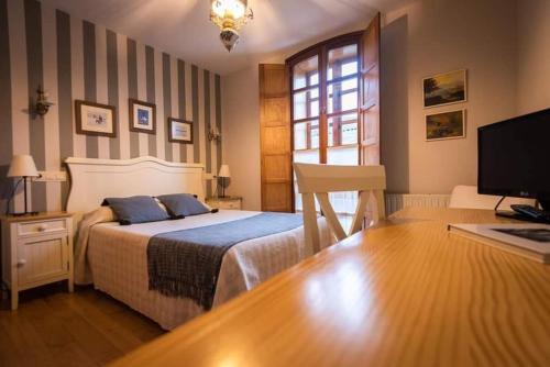 Villanueva de Oscos的住宿－HOTEL RURAL OSCOS，一间卧室配有一张床、一张书桌和一台电视