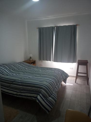 1 dormitorio con 1 cama con manta a rayas y ventana en Mukanga en San Pedro