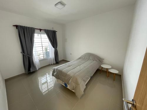 1 dormitorio con cama, mesa y ventana en Departamento Dalmacio en La Rioja