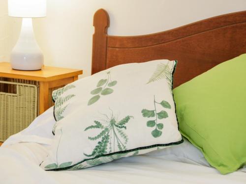 a pillow sitting on a bed next to a lamp at Dolwen in Betws-y-coed