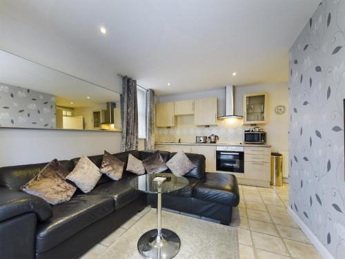 a living room with a black leather couch and a table at Sunrise Suite in Blackpool