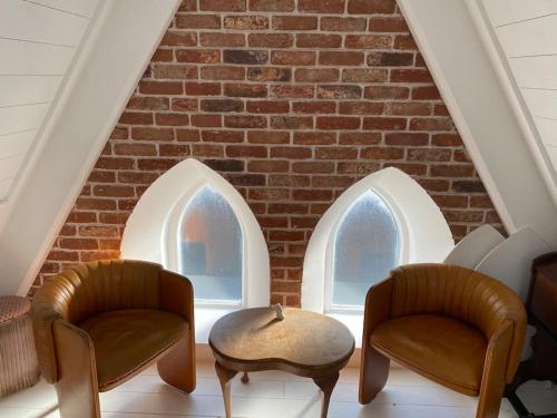 two chairs and a table in front of a brick wall at Chapel Theatre House in Sandgate