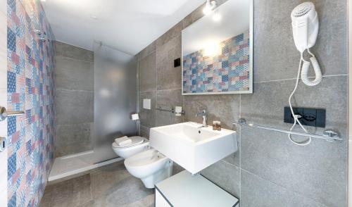 La salle de bains est pourvue d'un lavabo blanc et de toilettes. dans l'établissement Mini Suite con 1 Camera da letto (4 adulti), à Riccione