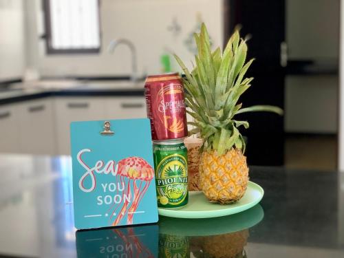 a plate with two pineapples and a bottle of beer and two pineapple at Sea La Vie - Holiday Home in Albion