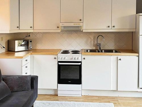 a kitchen with white cabinets and a stove and a sink at Holiday home INGARÖ VI in Lillängsdal