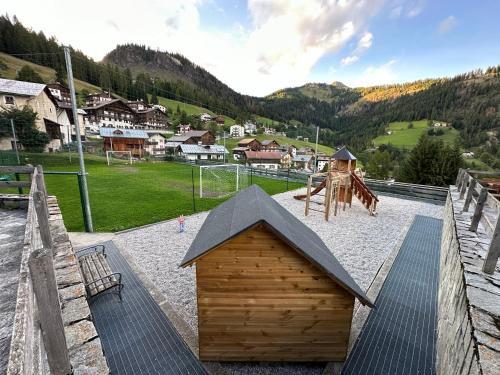 uma área de lazer com uma pequena casa de madeira e um parque infantil em Tabia Suite Pelmo em Villagrande